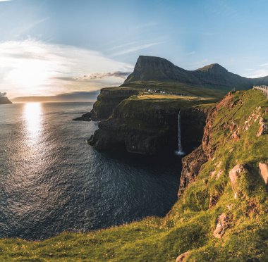 Gasadalur köyü ve Mulafossur 'un ikonik şelalesi, yaz boyunca Bluw Sky ile birlikte. Vagar, Faroe Adaları, Danimarka. Kuzey Atlantik Okyanusu 'nda zor bir durum..