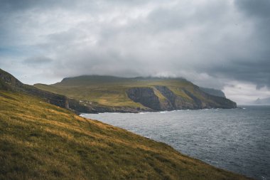 Yeşil çimen manzarası ve Atlantik Okyanusu olan güzel Mykines Adası. Mykines Adası, Faroe Adaları, Avrupa.