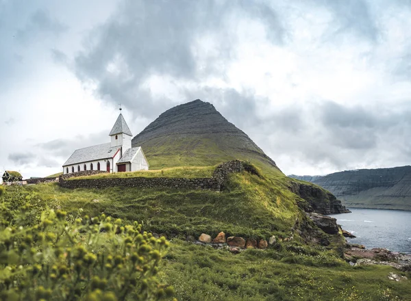 Θέα στην εκκλησία του Βιδαρείδι που ονομάζεται επίσης Βιδαρείδι Κίρκια με μουντό συννεφιασμένο ουρανό, ομίχλη και βουνά. Νήσοι Φερόε, Δανία, Ευρώπη. — Φωτογραφία Αρχείου