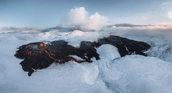 活発な溶岩川の空中パノラマは、アイスランド南西部のファグラダールゲリンダデール渓谷の火山噴火によって流れます。雪の山と青空。噴火は3月現在進行中である。 — ストック写真