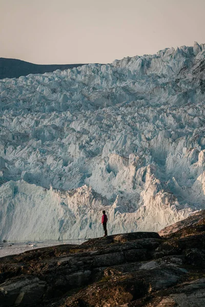 Persone non identificate sedute in piedi davanti a un enorme muro di ghiaccio. Ghiacciaio Eqip Sermia Ghiacciaio Eqi in Groenlandia chiamato ghiacciaio del parto durante il sole di mezzanotte. Escursionisti durante il viaggio e — Foto Stock