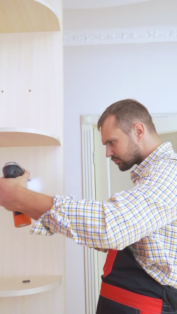 Verticale. Jeune assembleur de meubles masculins assemble une armoire intégrée — Video