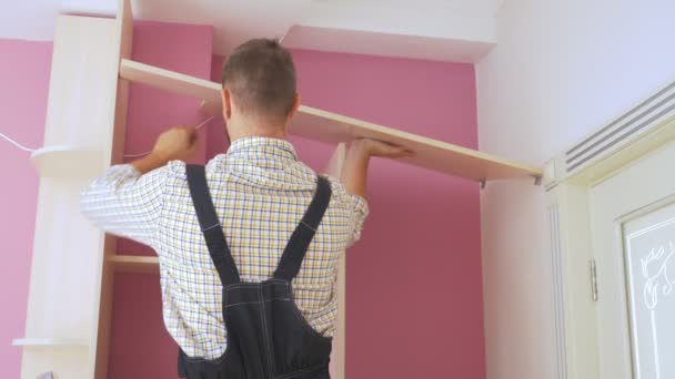 Unga manliga möbelmontörer monterar en inbyggd garderob — Stockvideo