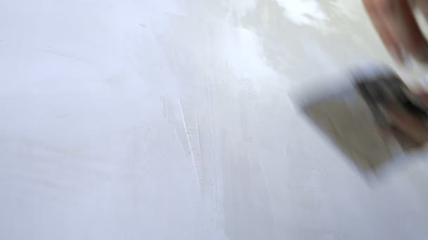 Gros plan d'une main. un homme applique du plâtre avec une truelle au mur — Video