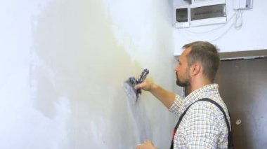 Genç yakışıklı müteahhit duvara bir malayla sıva yapıyor. ev onarımı