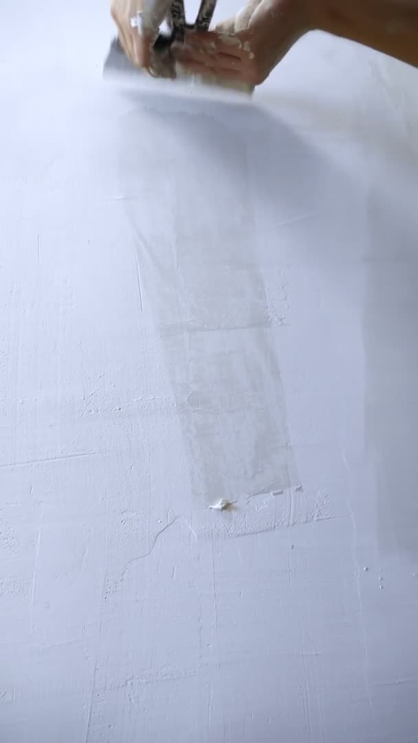 Perto de uma mão. um homem aplica gesso com uma espátula na parede — Vídeo de Stock