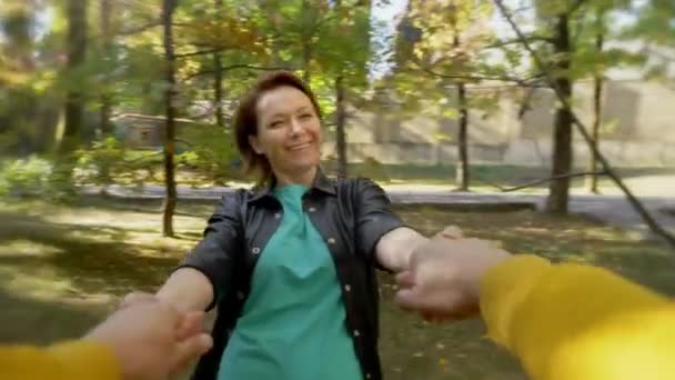 Vista em primeira pessoa. uma mulher gira segurando um homem mãos no parque — Vídeo de Stock