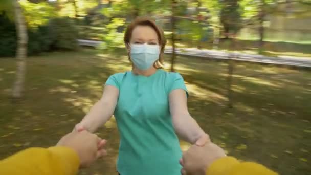 Visão em primeira pessoa, uma mulher está girando segurando as mãos de um homem em um parque de outono — Vídeo de Stock