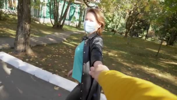 Vista in prima persona, una donna con una maschera medica conduce un uomo per mano — Video Stock
