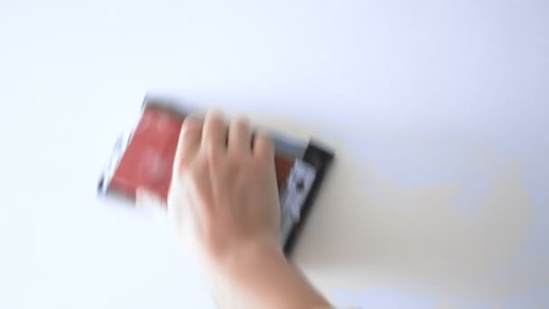 Рабочий в респираторе шлифует стену наждачной бумагой — стоковое видео