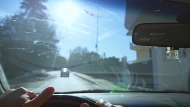 Şehirde araba süren bir adamın birinci şahıs görüntüsü. Güneş parlıyor — Stok video