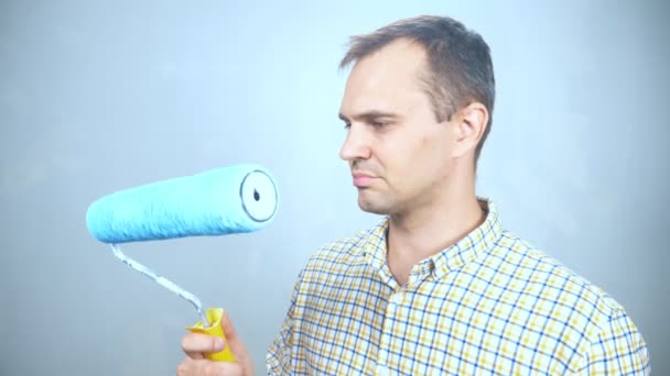 Retrato de un hombre mirando su rodillo de pintura. mirando a la cámara sonriendo — Vídeos de Stock