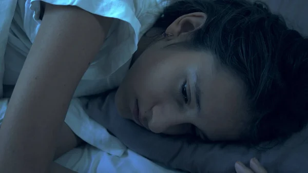 Portret van een tiener meisje dat lijdt aan slapeloosheid liggend in bed 's nachts — Stockfoto