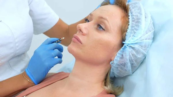 The beautician marks the injection points on the womans face with a pencil — Stock Photo, Image