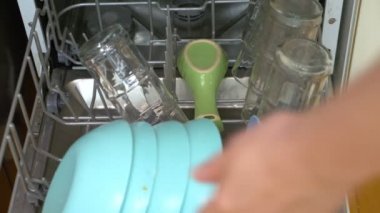 Elleri yakın çekim. Kadın bulaşık makinesine bulaşık koyar.