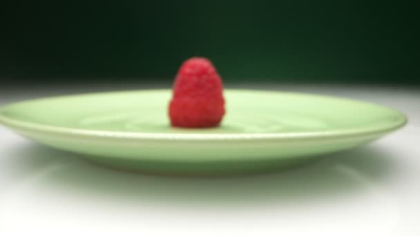 Очень крупным планом, детально. одинокая ягода спелой красной малины на тарелке — стоковое видео