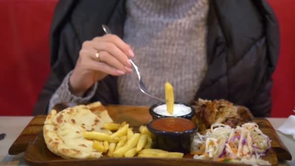 Donna in maglione e giacca mangiare giroscopi con patatine fritte in un bar fast food — Video Stock