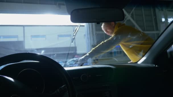 Vista desde el interior del coche. un hombre lavando un coche en un lavadero de coches — Vídeo de stock