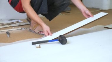 Yakın plan. Erkek eller içeri beyaz lamine döşüyorlar.