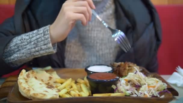 Femme en pull et veste manger gyros avec des frites dans un café de restauration rapide — Video