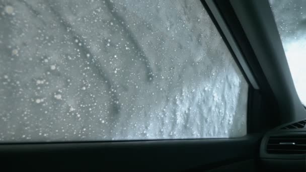 Blick aus dem Inneren des Autos. ein Mann wäscht ein Auto in einer Waschanlage — Stockvideo