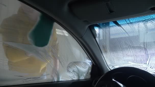 pohled zevnitř auta. muž myjící auto v myčce aut