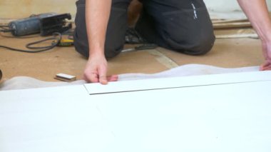 Yakın plan. Erkek eller içeri beyaz lamine döşüyorlar.