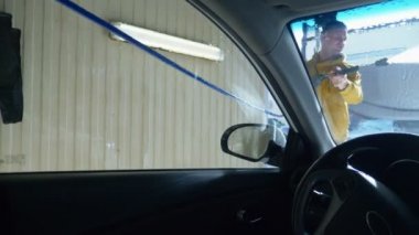 Arabanın içinden görüntü. Araba yıkamada araba yıkayan bir adam.