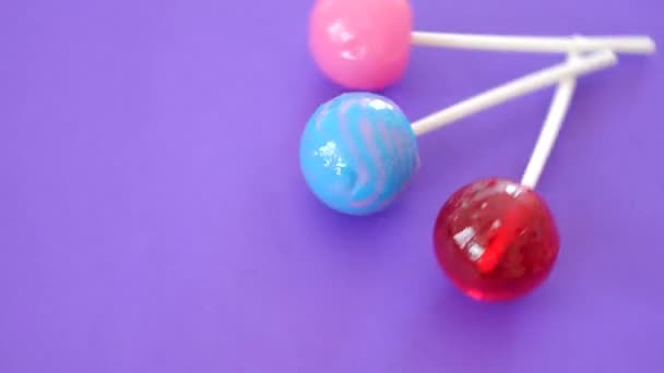 紫色背景上的彩色棒棒糖旋转。4k. — 图库视频影像