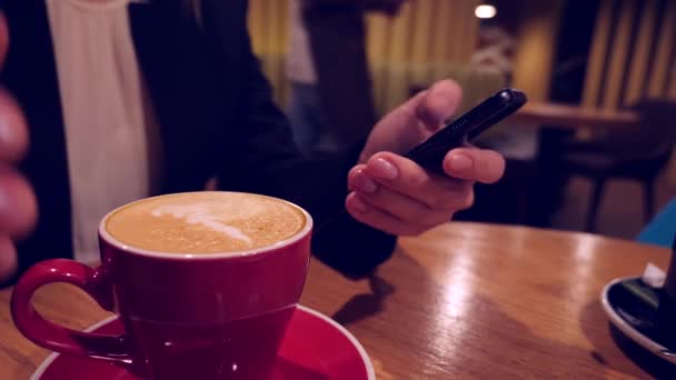 Empresaria manos mensajes de texto, el envío de SMS en el teléfono inteligente y beber café en la cafetería. 4k, cámara lenta. — Vídeo de stock
