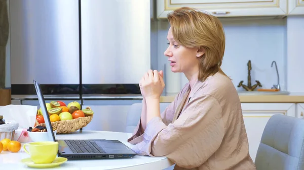 Kobieta komunikują się przez połączenie wideo za pośrednictwem laptopa podczas siedzenia przy stole w domu — Zdjęcie stockowe