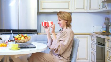 Kadın evinde dizüstü bilgisayarın önünde otururken hediye kutusunu açıyor.. 