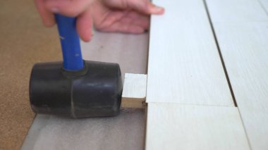 Yakın plan. Erkek eller içeri beyaz lamine döşüyorlar.