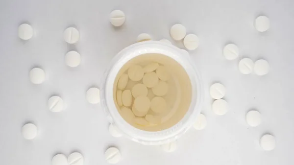 Close-up extremo, detalhado. pílulas derramadas em um frasco, vista superior, fundo branco — Fotografia de Stock