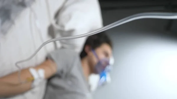 Blurred background. man with oxygen mask and dropper on hospital bed — Stock Photo, Image