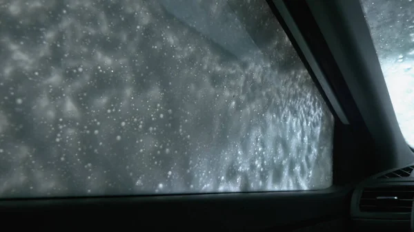 Vista de dentro do carro. um homem lavando um carro em uma lavagem de carro — Fotografia de Stock