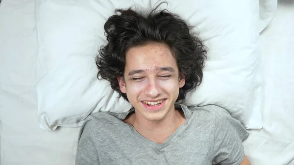 Vista desde arriba. retrato de un joven guapo riendo tumbado en la cama — Foto de Stock