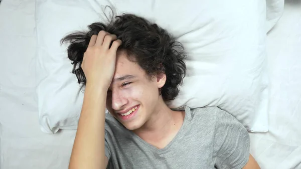 위에서 본 광경. 침대에 누워 웃고 있는 잘생긴 젊은 청년의 사진 — 스톡 사진