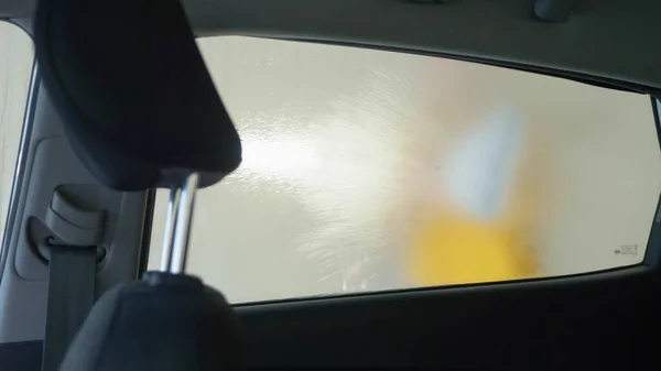 view from inside the car. a man washing a car at a car wash