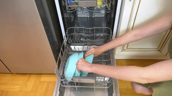 Mujer cargando platos en el lavavajillas en casa en su cocina — Foto de Stock