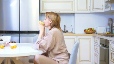 Gülümseyen, rüya gören kadın evinde çay içiyor.