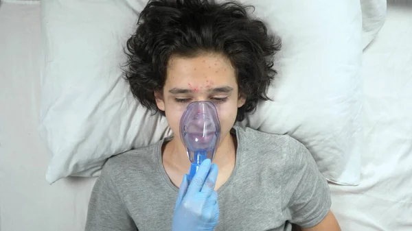 oxygen mask on the face of a guy lying on a bed in a hospital
