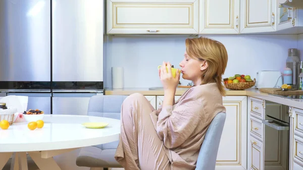 Hermosa mujer triste sentada a la mesa en la cocina con una taza — Foto de Stock