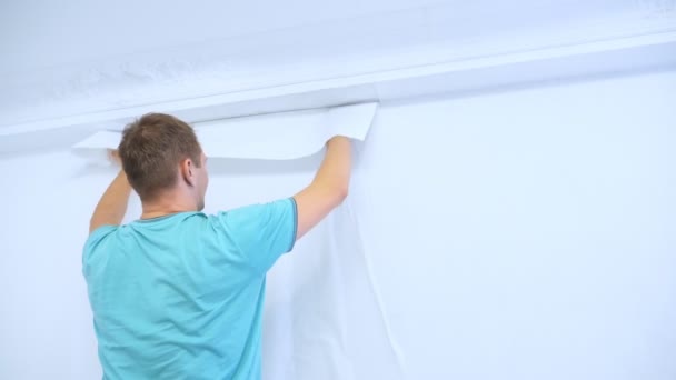 Muž v montérkách lepí tapety na zdi v bytě — Stock video