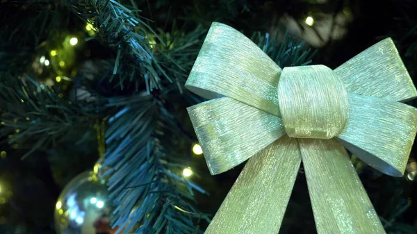 Close-up van gouden boog op kerstboom met gloeiende bloemenslingers — Stockfoto