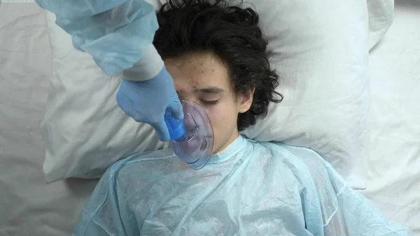 Oxygen mask on the face of a guy lying on a bed in a hospital Stock Photo