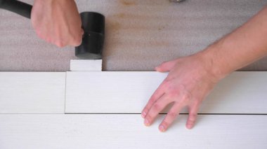 Yakın plan. Erkek eller içeri beyaz lamine döşüyorlar.