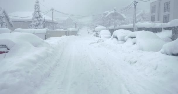 Utsikt över en snöig väg med bilar täckta med snö på sidorna — Stockvideo