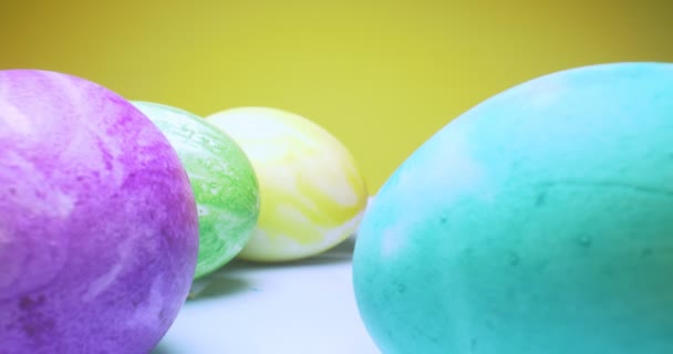 Close-up extremo detalhado de ovos coloridos multicoloridos em uma placa. fundo amarelo. decorações de Páscoa — Vídeo de Stock