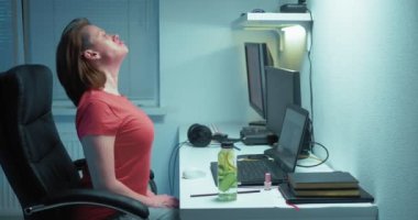 Kadın yüz jimnastiği yapıyor. Ev ofisinde dizüstü bilgisayar kullanıyor.